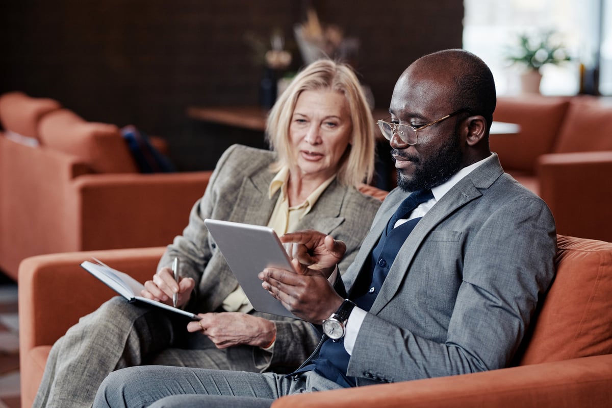 Business advisor explaining a plan on a tablet to a colleague making notes